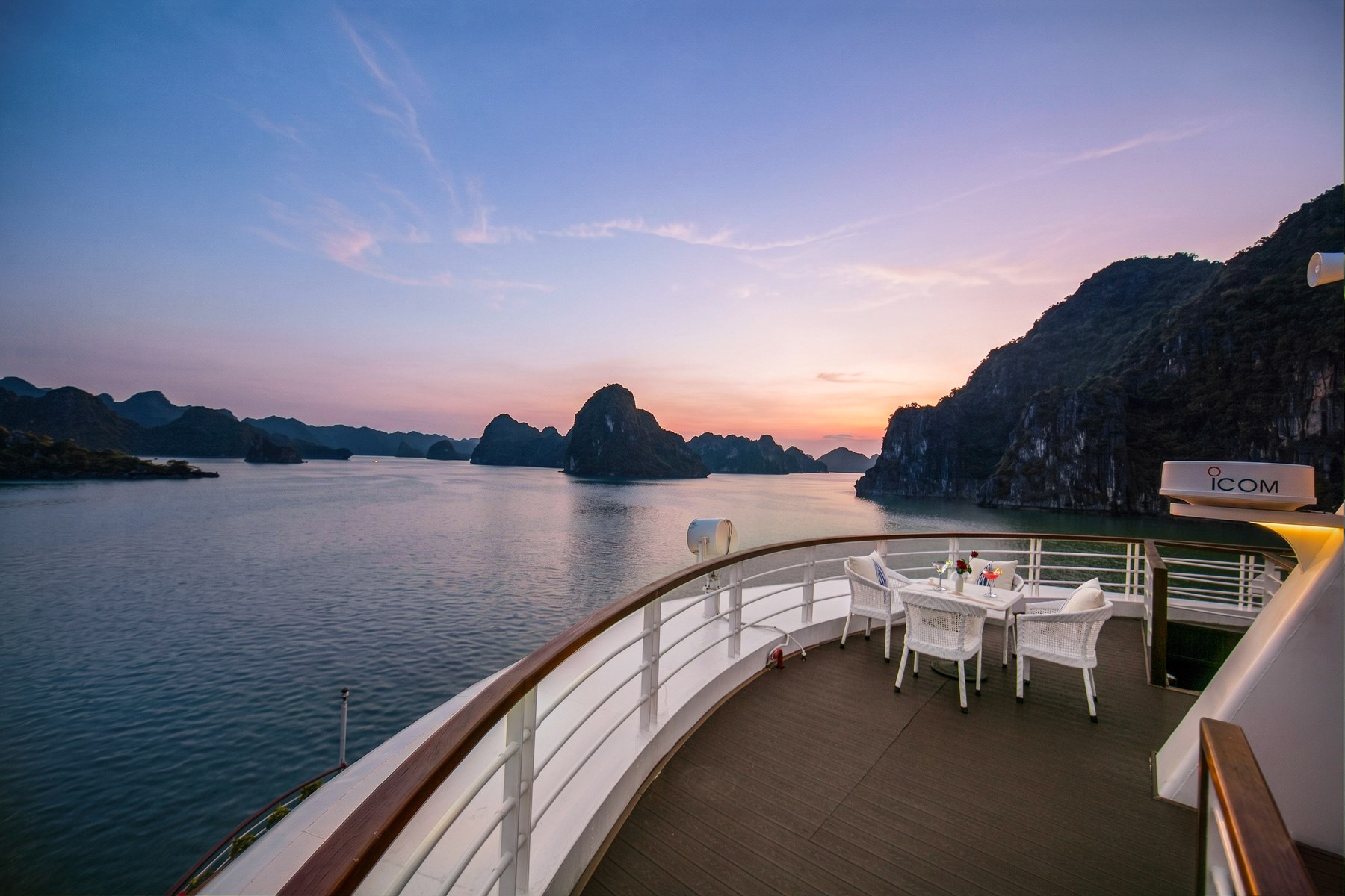 Dusk over Halong Bay seen from a white railing on the deck of Hermes Premium