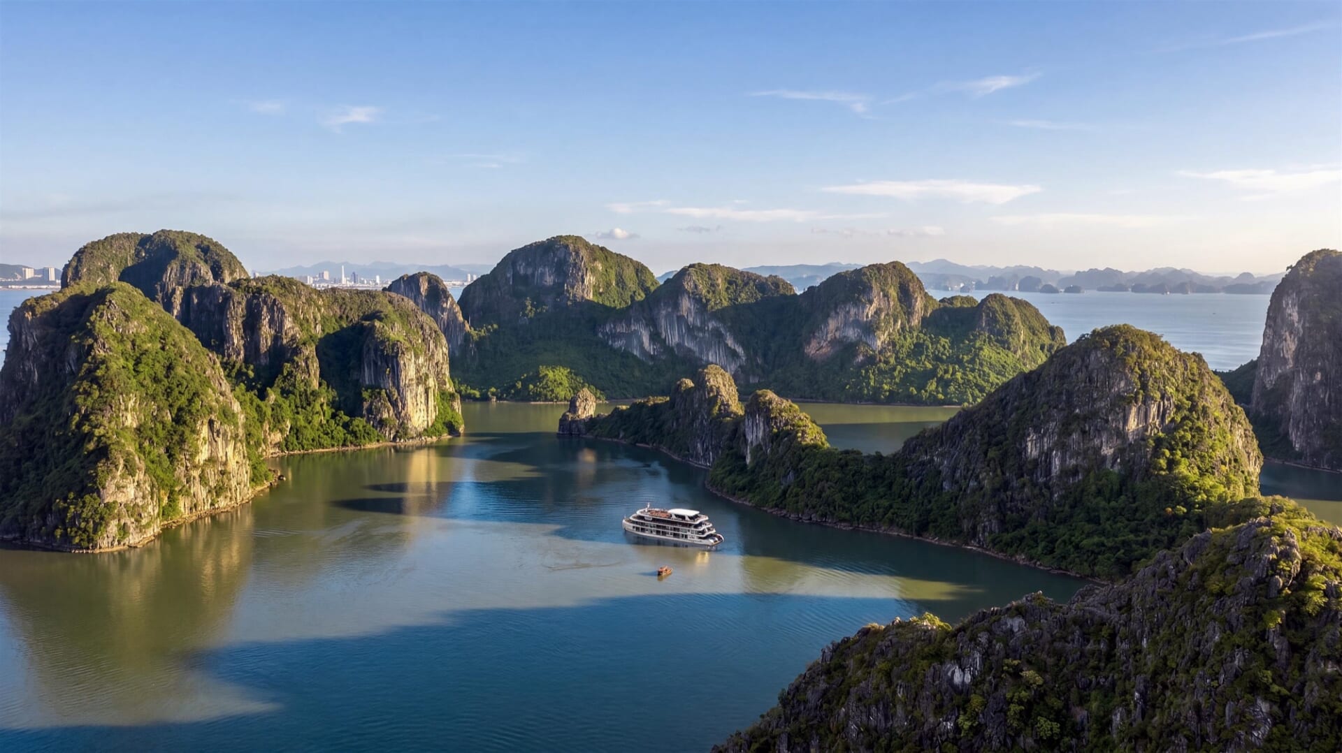 Hermes Premium seen from the water, a white multi-deck ship against a limestone island in Halong Bay